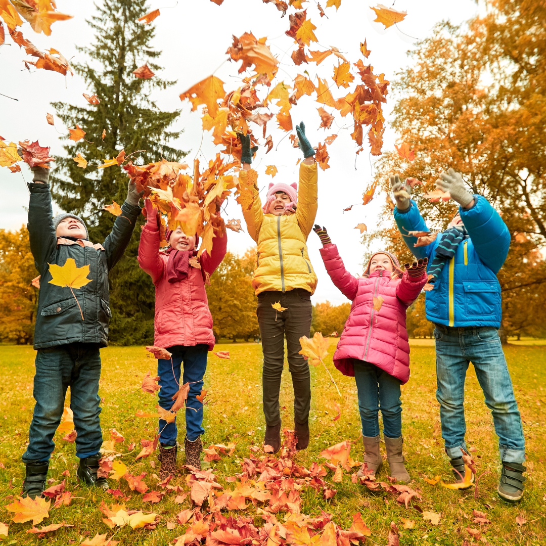 children throwing leaves in the air