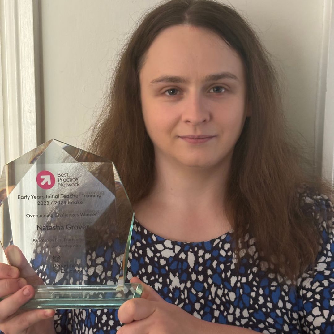 A woman with long brown hair holding a glass trophy to an EYITT award